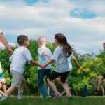 Group of children having fun and playing games together in a sunny park.