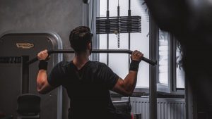 Back view of a man exercising with lat pulldown machine in the gym.